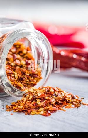 Séchez les flocons de piment. Poivrons rouges écrasés en pot sur la table blanche. Banque D'Images