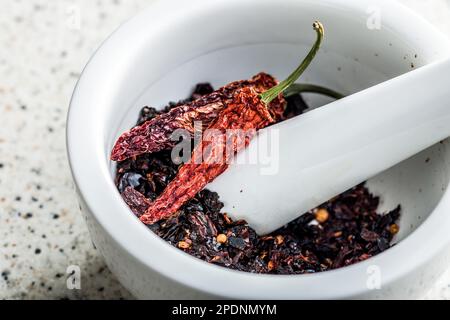 Séchez les flocons de piment. Poivrons rouges écrasés fumés dans le mortier. Banque D'Images