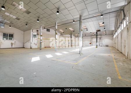 Garage de stationnement avec des lumières, des murs de couleur claire, des poutres métalliques et un plafond préparé pour la rénovation dans une salle de fête. Le concept de locaux spacieux Banque D'Images