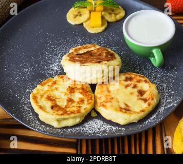 Crêpes au sirop ou au fromage avec sauce à la crème et bananes sur une assiette sur une table en bois Banque D'Images