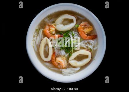 Soupe vietnamienne traditionnelle Pho avec fruits de mer sur fond noir Banque D'Images