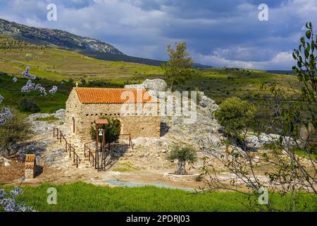 Petite chapelle par rocher avec toit de tuiles rouges et cloche, à l'intérieur des terres de la région de Phaphos Pafos de Chypre en hiver, soleil d'hiver Banque D'Images