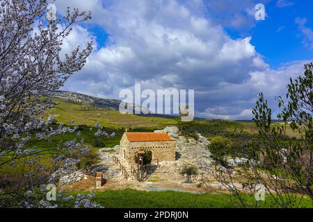 Petite chapelle par rocher avec toit de tuiles rouges et cloche, à l'intérieur des terres de la région de Phaphos Pafos de Chypre en hiver, soleil d'hiver Banque D'Images