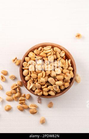 Grains de cacahuètes aromatisés épicés dans un bol sur fond de table blanc. Banque D'Images