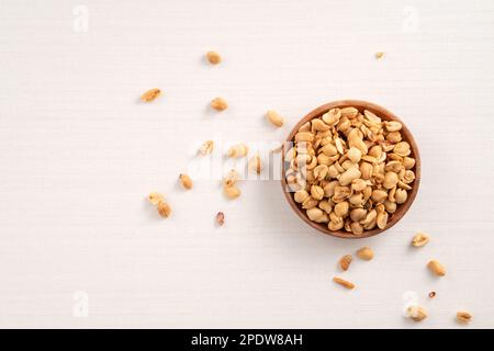 Grains de cacahuètes aromatisés épicés dans un bol sur fond de table blanc. Banque D'Images