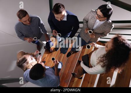 Groupe de collègues parlant pendant la pause-café dans les escaliers du bureau, vue de dessus Banque D'Images