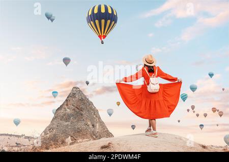 Fille regardant les ballons d'air chaud prendre le vol dans le paysage pittoresque de la Cappadoce. Elle portait une délicate robe d'été et un chapeau Banque D'Images