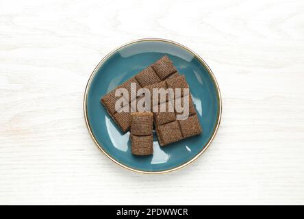Assiette bleue avec hématogène délicieux et sain sur table en bois blanc, vue du dessus Banque D'Images