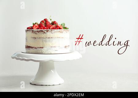 Délicieux gâteau avec baies fraîches et hashtag Wedding sur fond clair Banque D'Images