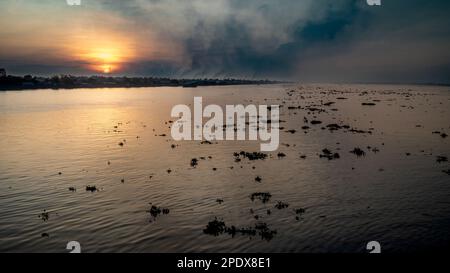 Une vue sur le Mékong avec ses amas de jacinthe d'eau flottante à long Xuyen dans le delta du Mékong au Vietnam. Smog des fours à briques à proximité Banque D'Images