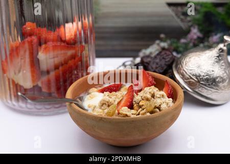 Petit déjeuner sain - céréales avoine, fraise, miel avec noix de yaourt dans le bol en argile Banque D'Images