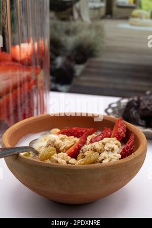 Petit déjeuner sain - céréales avoine, fraise, miel avec noix de yaourt dans le bol en argile Banque D'Images