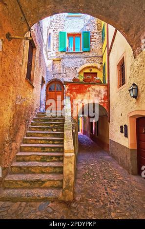 La vue à travers l'arche sur une rue étroite avec un escalier en pierre, menant à la maison médiévale en pierre, Oria, Valsolda, Italie Banque D'Images