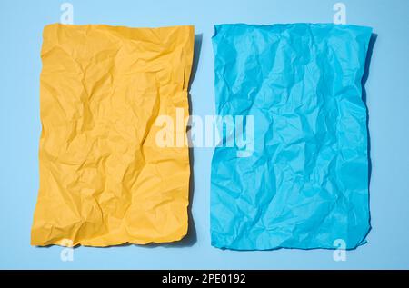 Deux feuilles de papier froissés, jaune et bleu sur fond bleu, espace pour une inscription Banque D'Images