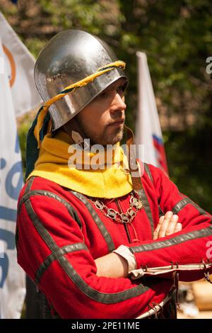 Khabarovsk, Russie - 11 juin 2017 : costume de la période du Moyen âge au tournoi de chevalier. Jeune homme portant un casque en métal et cotehardie rouge à m historique Banque D'Images