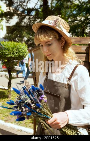 Khabarovsk, Russie - 11 juin 2018 : farmer holding bouquet de fleurs sauvages et de tenue. Belle fille pastorale dans un chapeau de paille et l'APRO Banque D'Images