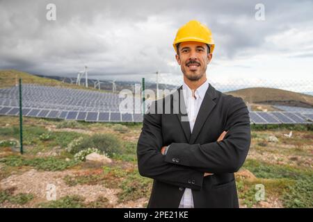 Un ingénieur d'une centrale solaire élégamment habillé porte un casque de protection. Banque D'Images