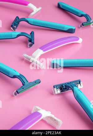 De nombreux rasoirs jetables de couleur violet et bleu sur fond rose. Accessoires d'hygiène colorés pour femmes et hommes. Mise au point au milieu Banque D'Images