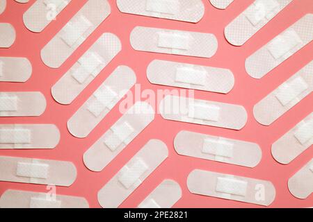 De nombreux rubans adhésifs blancs sont disposés sur fond rose. Motif de pansements adhésifs médicaux transparents Banque D'Images