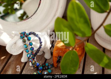 Verre de Murano bleu et perles de pierre sur une coiffeuse de dame. Choisir des bijoux pour accessoiriser devant un miroir Banque D'Images