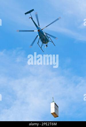 Vue de dessous de l'hélicoptère avec chargement volant dans le ciel bleu Banque D'Images