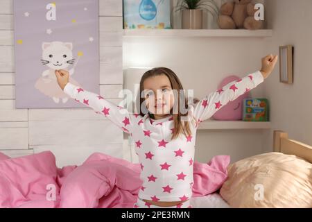 Jolie petite fille s'étirant près du lit à la maison Banque D'Images