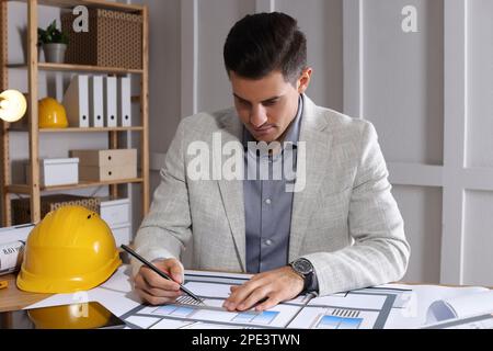 Architecte travaillant avec des dessins de construction dans le bureau Banque D'Images