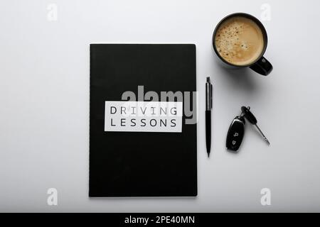 Composition avec cahier d'exercices pour les leçons de conduite sur fond blanc, vue de dessus. Réussite de l'examen de licence Banque D'Images