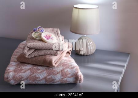 Pile de vêtements avec de beaux sachets de cire parfumés sur table grise à l'intérieur Banque D'Images