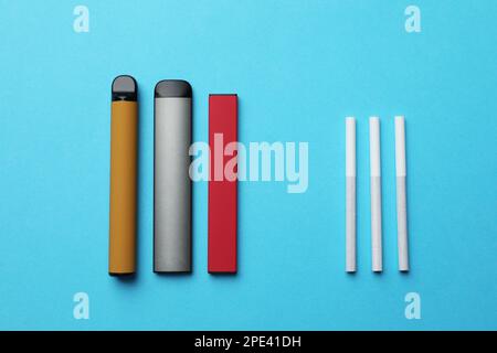 Cigarettes électroniques et régulières sur fond bleu clair, sur fond plat Banque D'Images