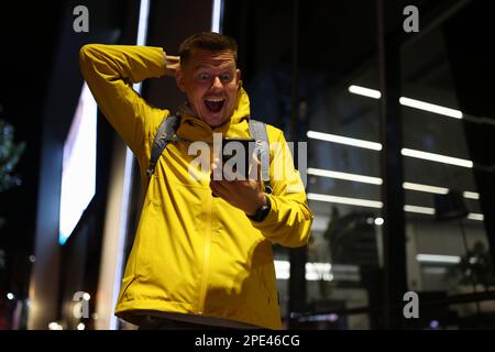Surprise voyageur avec la bouche ouverte regardant l'écran de smartphone dans la rue. Banque D'Images