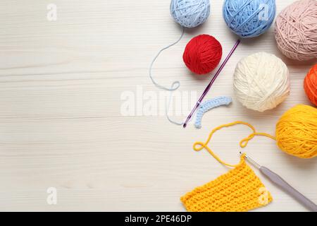 Composition de pose plate avec fils à tricoter et crochets sur table blanche en bois, espace pour le texte Banque D'Images
