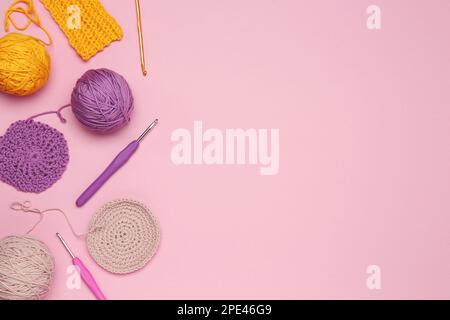 Composition de pose à plat avec fils à tricoter et crochets sur fond rose, espace pour le texte Banque D'Images