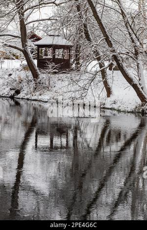 Un petit belvédère en bois dans les profondeurs d'une forêt d'hiver près d'un ruisseau de montagne froid et noyés marchent le long de lui, grimpant d'une vallée forestière. Banque D'Images