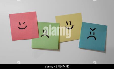 Collez les notes sur fond blanc. Papiers pense-bête avec smiley visages. Un visage souriant, triste, heureux et en colère. Banque D'Images