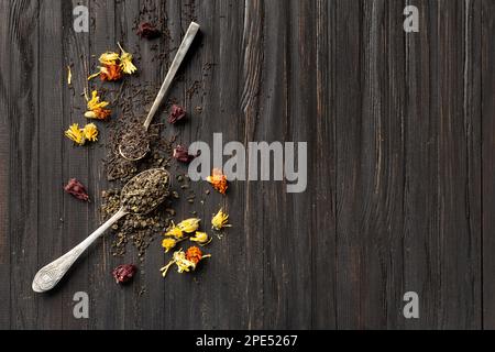 Composition de thé noir et vert sec dans des cuillères vintage et hibiscus sec, fleurs calendula sur un fond de bois foncé vue du dessus de l'espace de copie. Banque D'Images
