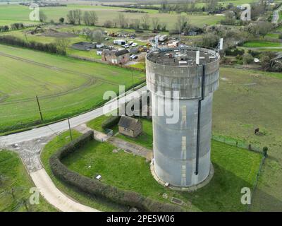 Vue de drone d'une tour d'eau en béton qui a un réseau de 5G antennes sur son toit circulaire. Situé dans un endroit rural à East Anglia Banque D'Images