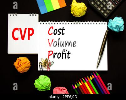 Symbole de profit de volume de coût CVP. Concept mots CVP coût volume profit sur note blanche sur fond noir magnifique. Crayon et stylo. Calculatrice. Entreprise Banque D'Images