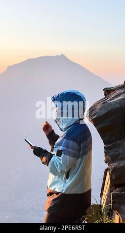 L'homme salue le lever du soleil dans les montagnes. Un homme salue l'aube. Java Ouest, Indonésie, 16 mars 2023 Banque D'Images