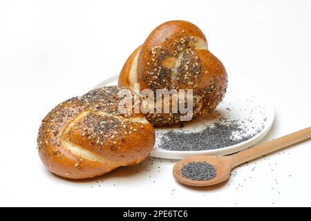 Petits pains aux graines de pavot, graines de lin et graines de sésame, bretzel roulé avec graines de pavot bleues dans une cuillère à cuisson Banque D'Images