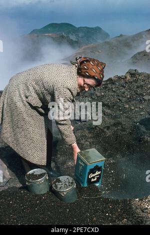 Femme qui cuit du pain dans la chaleur de la coulée de lave, volcan Eldfell, Heimaey, îles Westman, Islande, Juin 1976 Banque D'Images