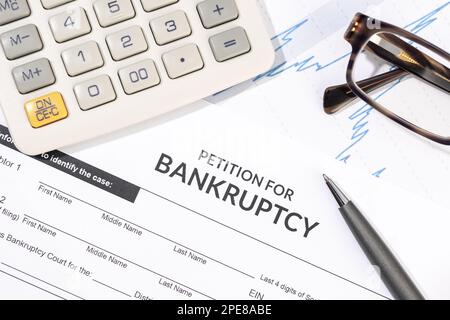 Formulaire de faillite, calculatrice et stylo sur le bureau. Formulaire de réclamation pour dommages corporels. Vue de dessus Banque D'Images