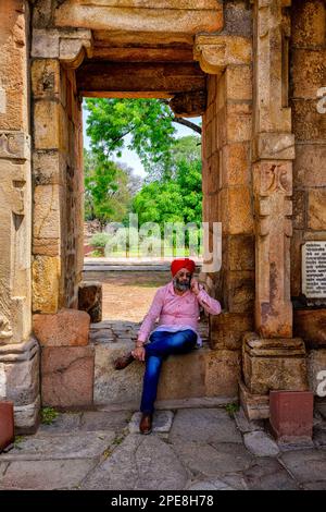 Au téléphone au milieu des colonnes du cloître dans la mosquée Quwwat ul-Islam au complexe Qutub Minar, Delhi, Inde Banque D'Images