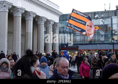 Un partisan du président russe Vladimir Poutine porte un drapeau sur la place Komsomolskaya. Le drapeau porte un portrait de Poutine. Le texte sur le drapeau dit: «Pour la mère patrie! Pour la souveraineté! Pour Poutine!". Banque D'Images