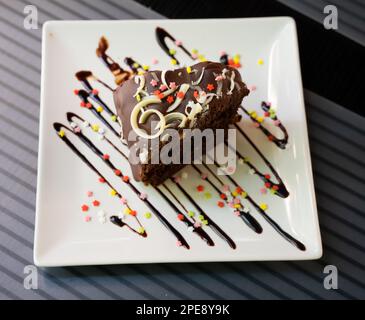 Savoureuse tranche de gâteau au brownie posée de façon décorative sur une assiette Banque D'Images