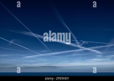 Ciel bleu avec grille de White condensation sentiers, contrails, de l'avion sur la côte atlantique en France Banque D'Images