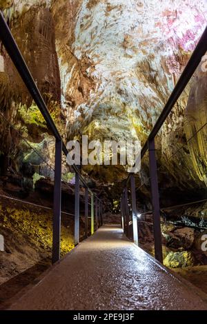 Chemin avec des rampes métalliques à travers le monument naturel illuminé de la grotte Prométhée - plus grande grotte de Géorgie avec des stalactites et des stalagmites. Banque D'Images