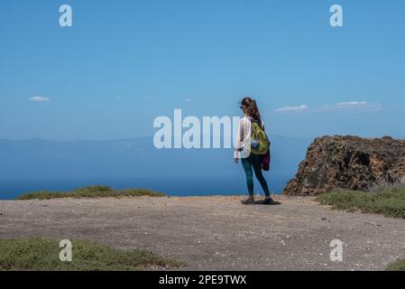 Un jeune randonneur s'arrête pour admirer la vue sur l'océan et l'île depuis le circuit Cavern point sur l'île de Santa Cruz, qui fait partie du parc national des îles Anglo-Normandes. Banque D'Images