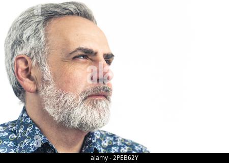 Vue latérale d'un homme barbu aux cheveux gris avec une expression réfléchie. Gros plan - isolé sur fond blanc. Photo de haute qualité Banque D'Images
