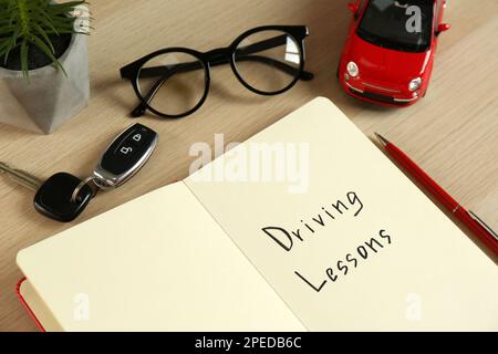 Manuel de cours de conduite avec stylo et voiture-jouet sur table en bois blanc. Réussite de l'examen de licence Banque D'Images